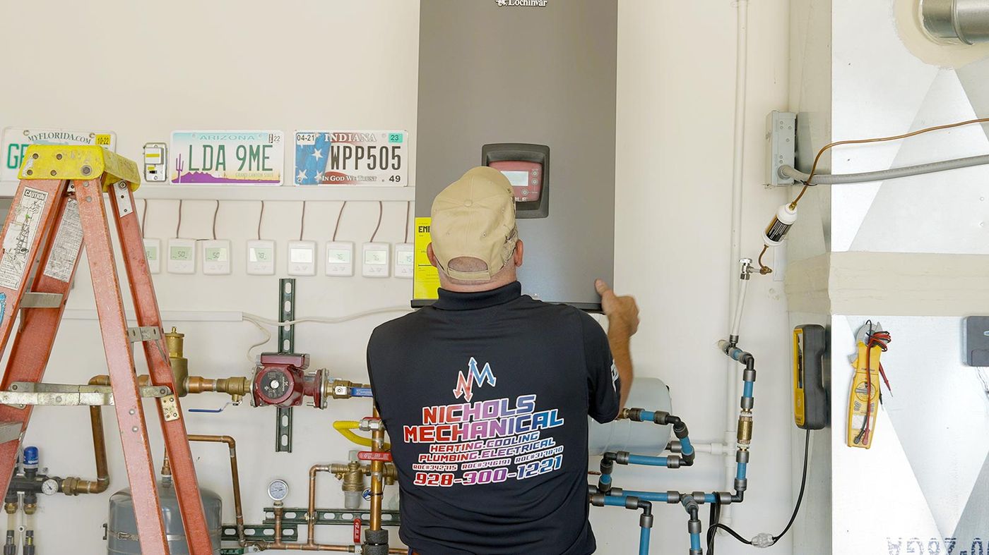 Nichols plumber working on a wall-mounted tankless water heater